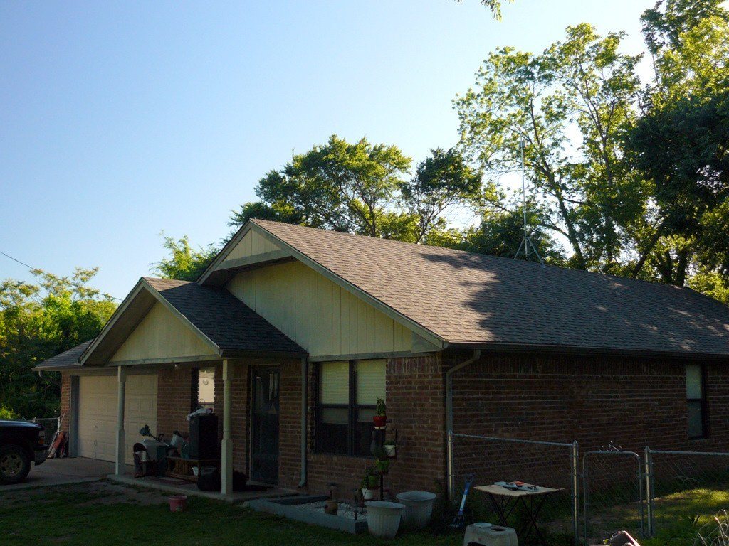 Brick bungalow with a fresh shingle roof under a clear sky